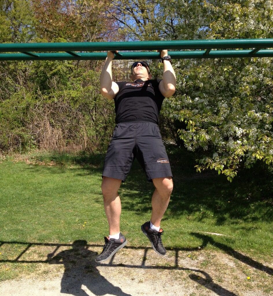 A man doing pull ups on a pull up bar.