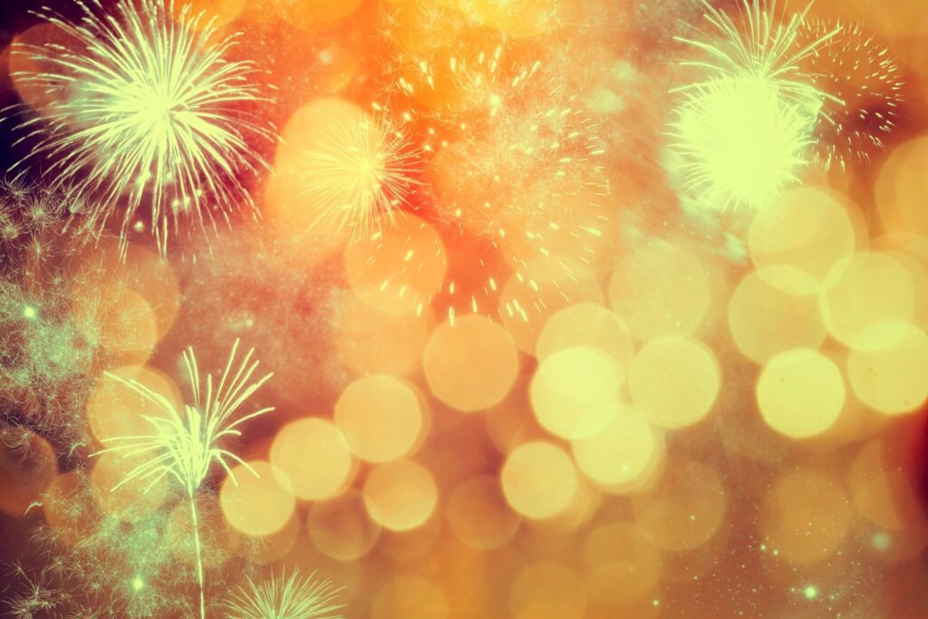 Fireworks on a golden background with bokeh lights.