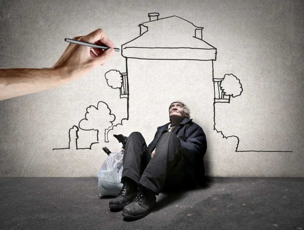 A homeless man sitting on the ground with a drawing of a house.