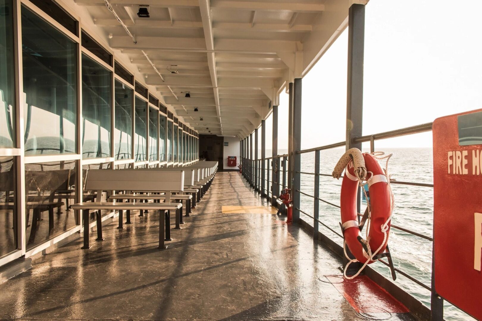 The deck of a ferry with benches and a life preserver.