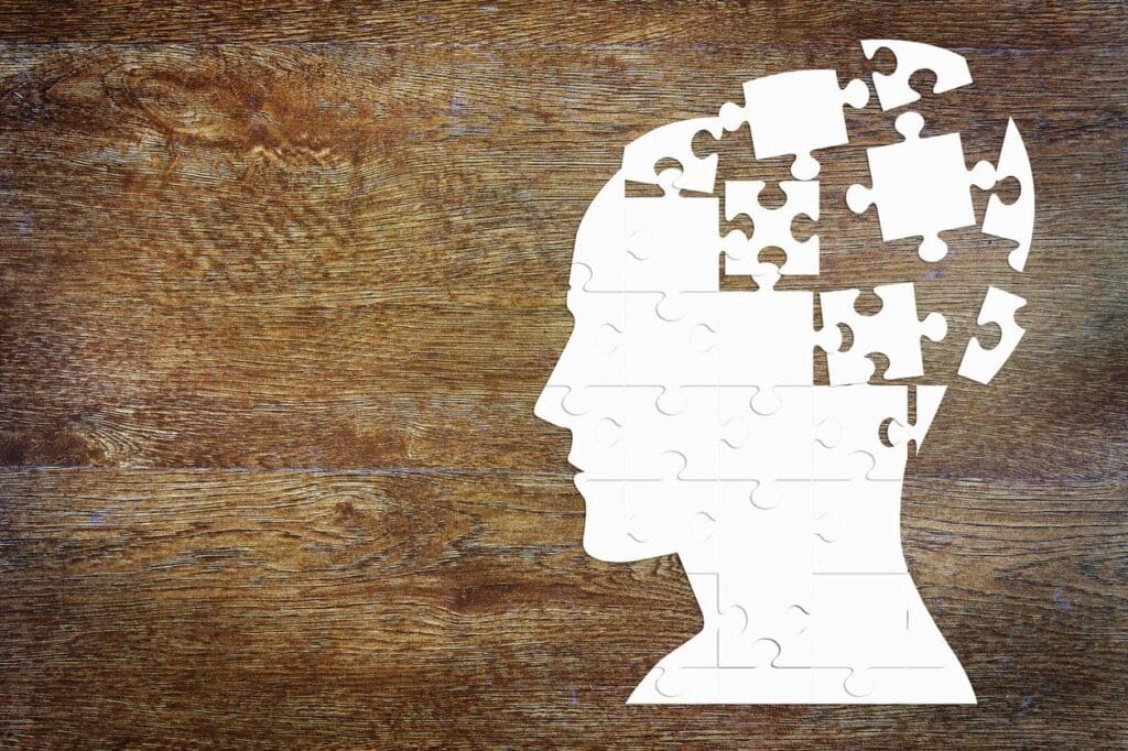 A man's head with puzzle pieces on a wooden background.