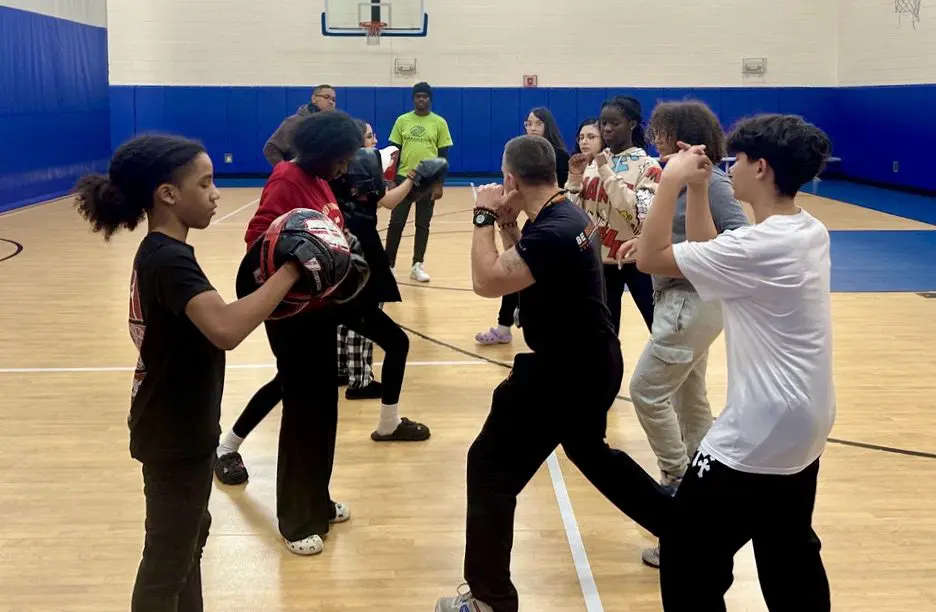 A group of young people practicing martial arts for self-defense in a gym.