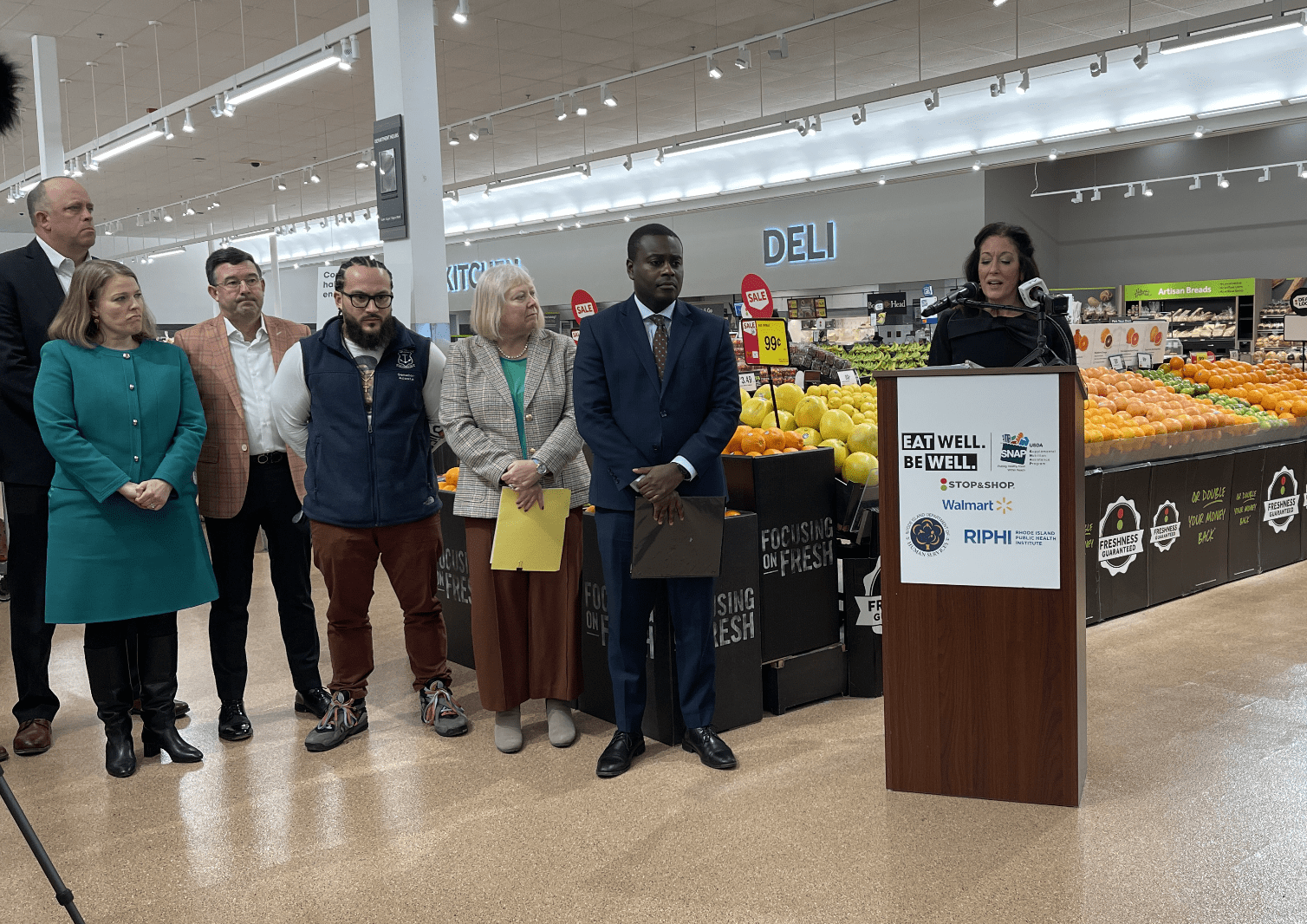 A group of people standing in front of a grocery store accepting SNAP.