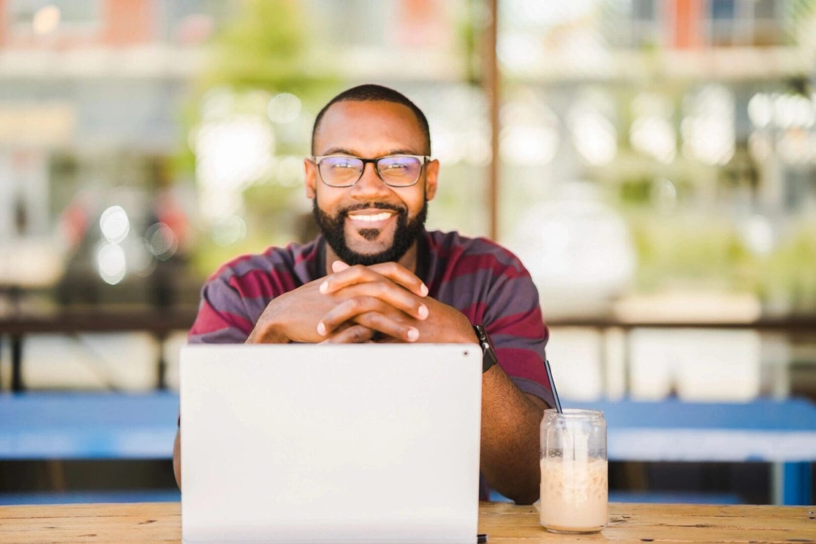 A black man sitting at a table with a laptop.