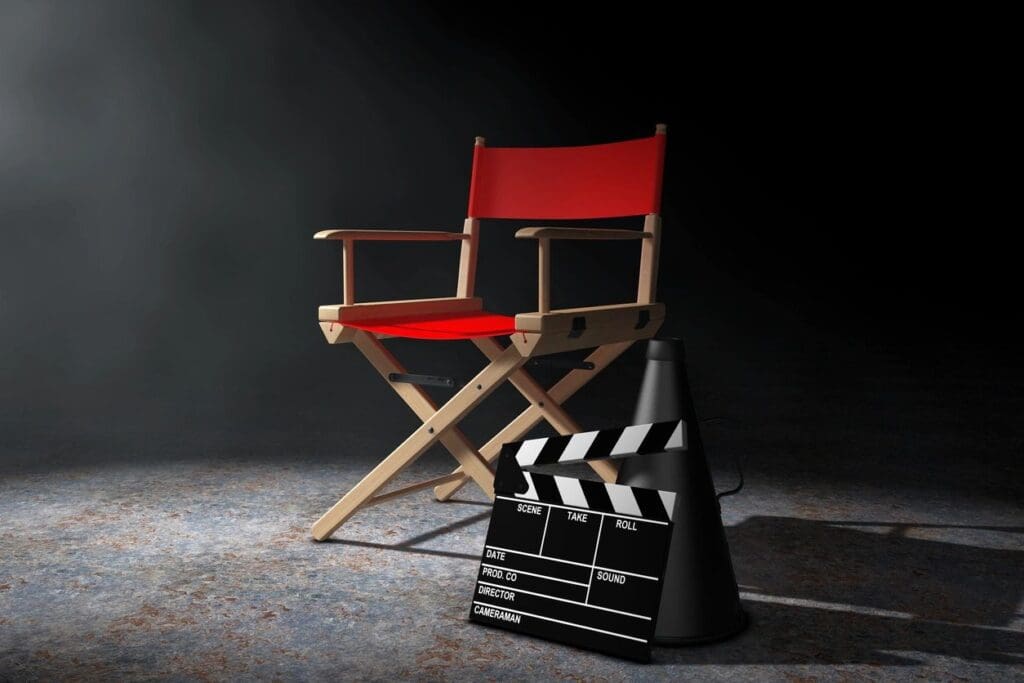 A red director's chair and clapboard on a dark background.
