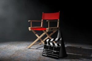 A red director's chair and clapboard on a dark background.
