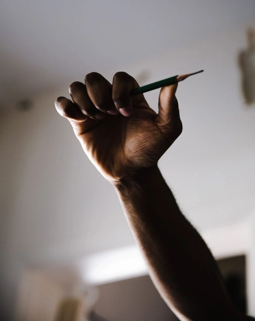 A hand holding a pencil up in the air.