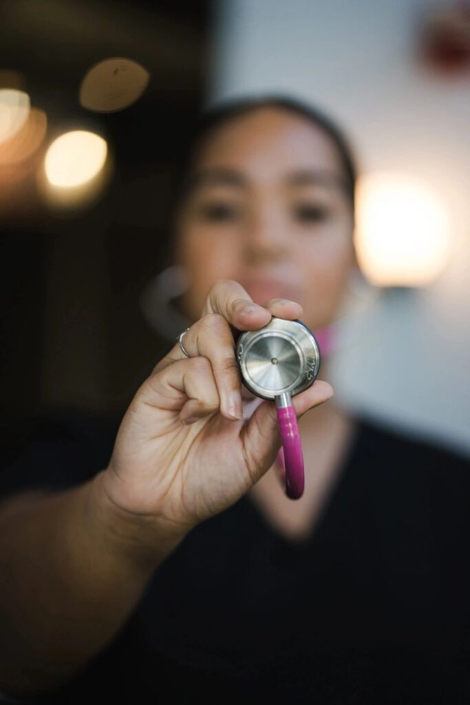 A nurse holding a pink stethoscope.