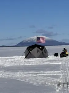A tent on the ice with an american flag in the background.