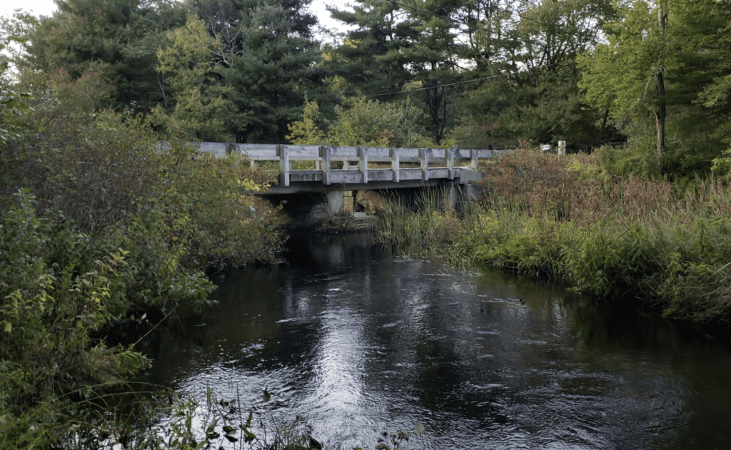A bridge closure over a river in a wooded area.