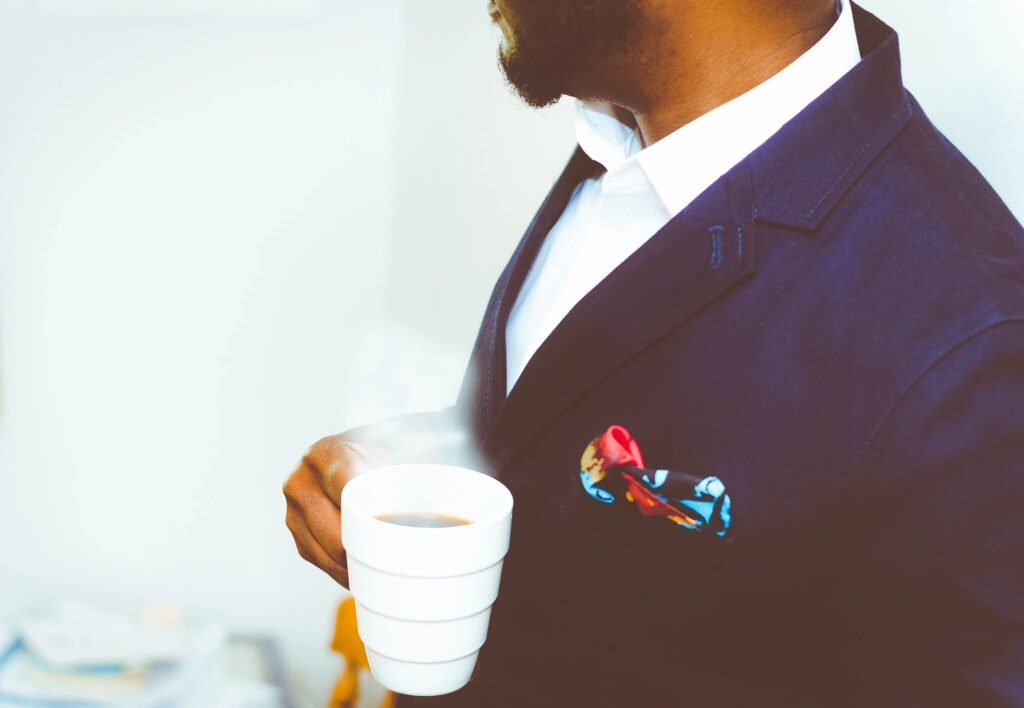 A man in a suit is holding a cup of coffee.