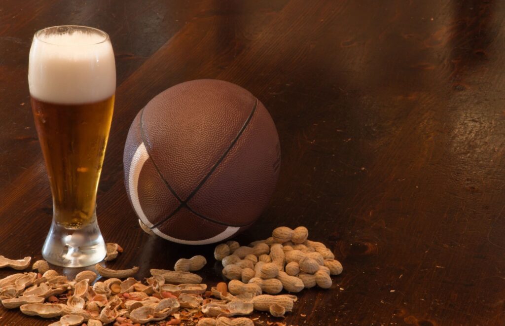 A glass of beer and peanuts on a table.
