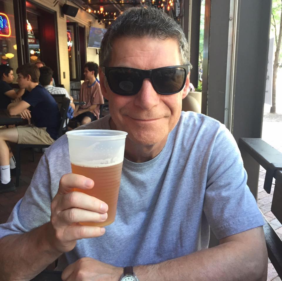 A man in sunglasses, Ron St. Pierre, holding a glass of beer.