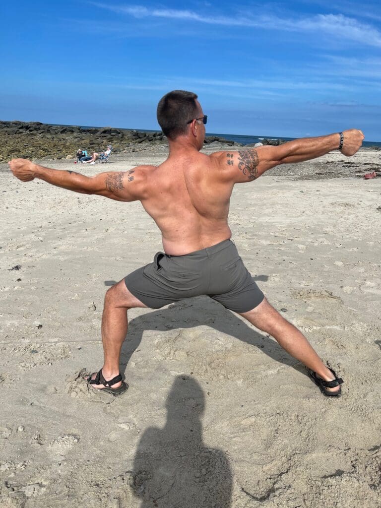 A man doing a fitness yoga pose on the beach.