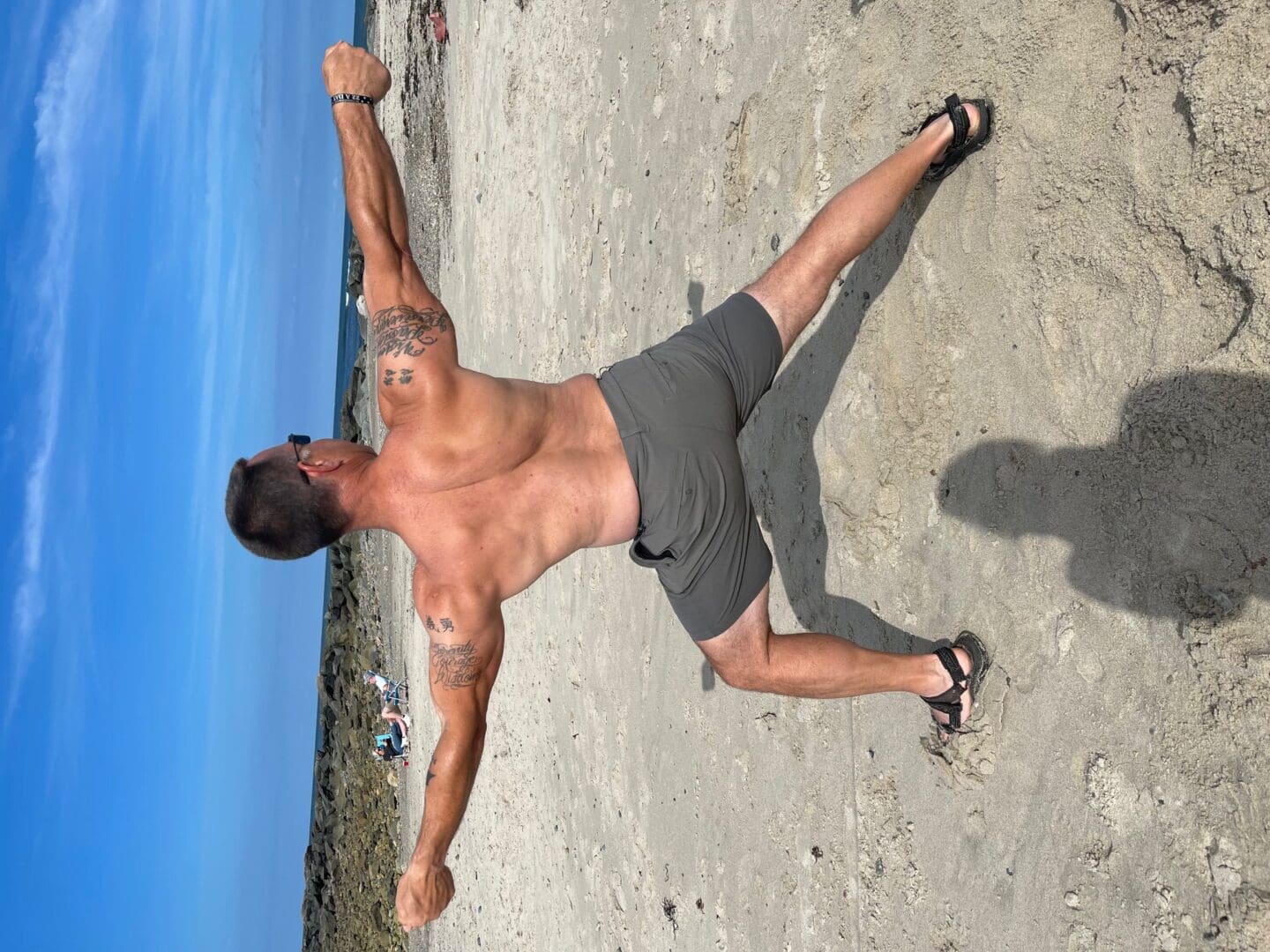 A man doing a fitness yoga pose on the beach.