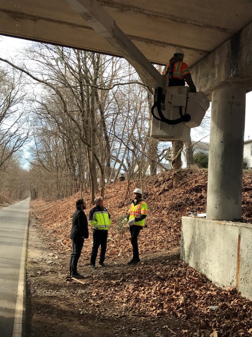 A group of people standing under the Cranston Bridge for inspections.