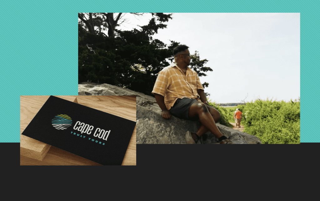 A man sitting on a rock with a Cape Cod Tourism business card.