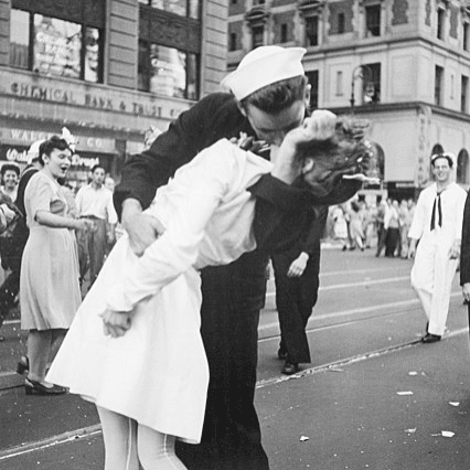 A veteran sailor kisses a woman on the street.