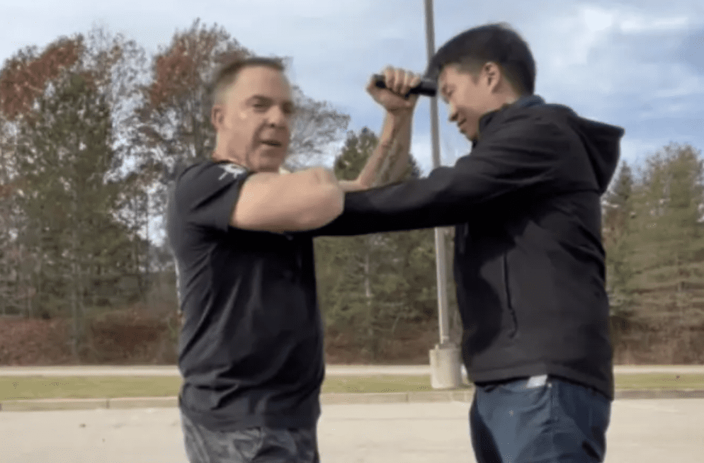Two men in a parking lot exercise fighting each other.