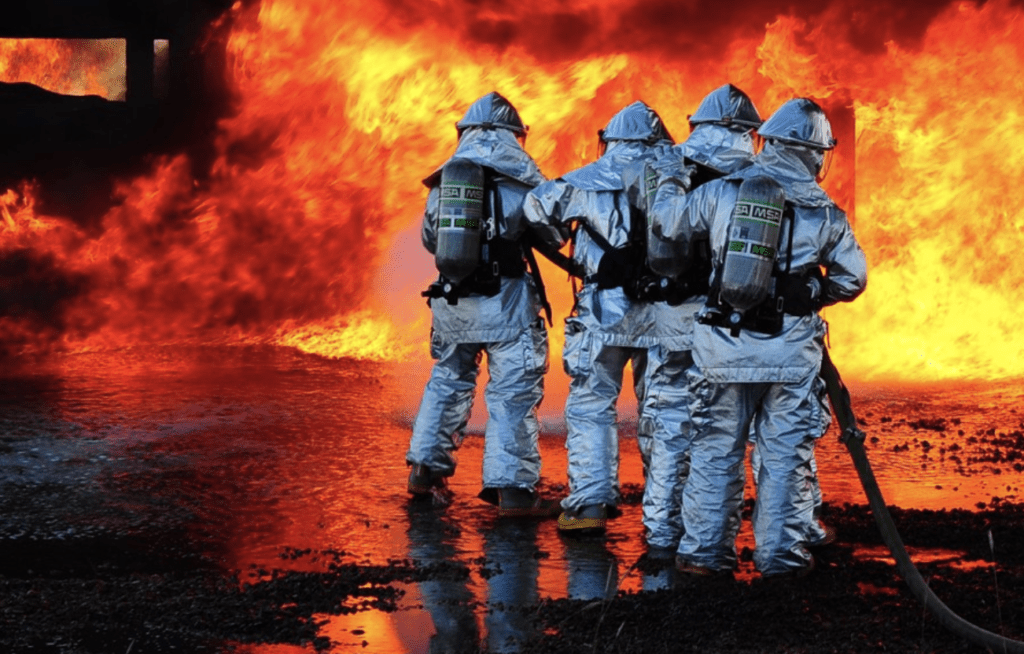 A group of firefighters standing in front of a fire, ready to deploy firefighting foam.