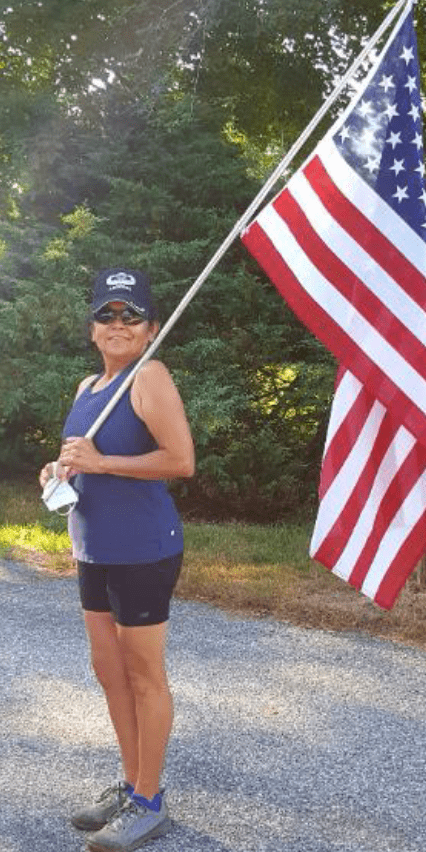 A woman holding an american flag on a road to honor veterans.
