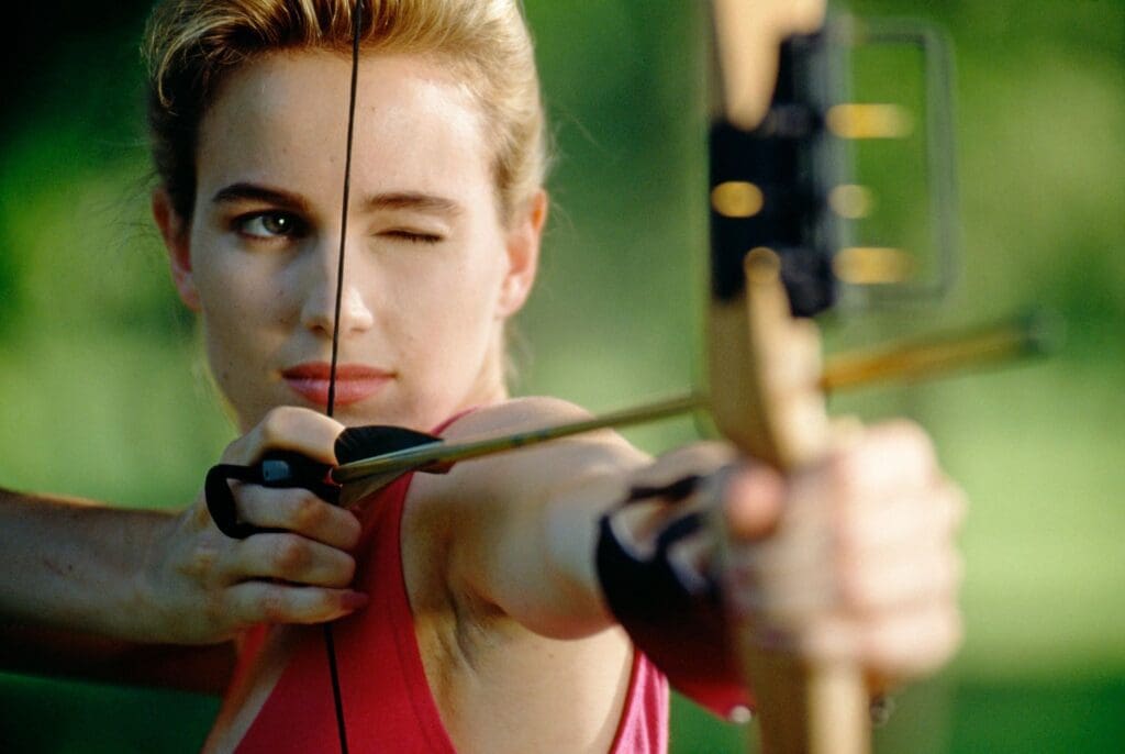 A woman aiming at a target with a bow and arrow.