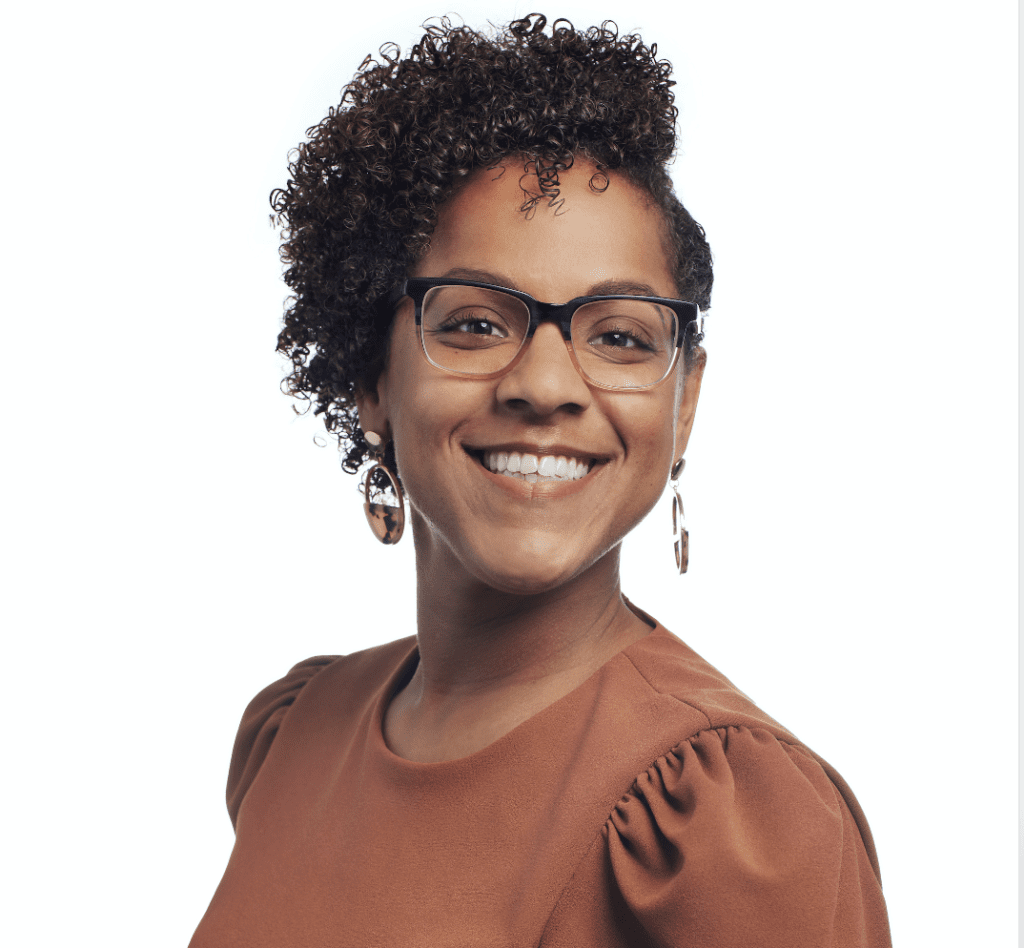 Smiling woman with glasses and curly hair.