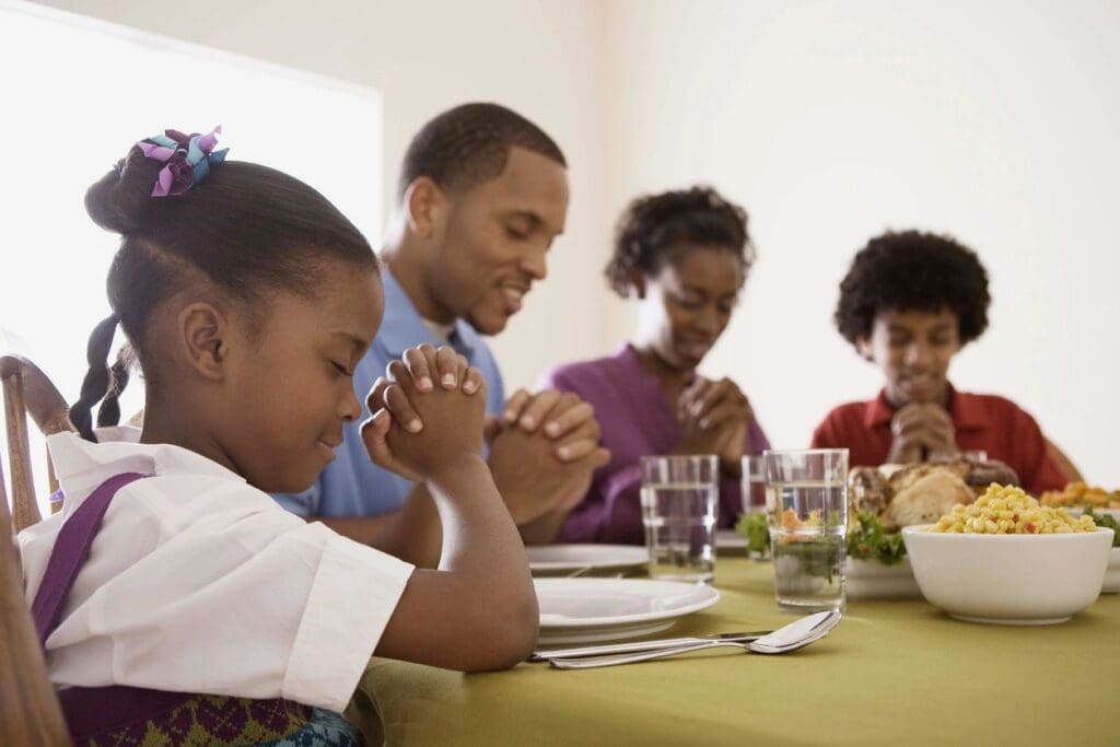 Family praying before Thanksgiving meal.