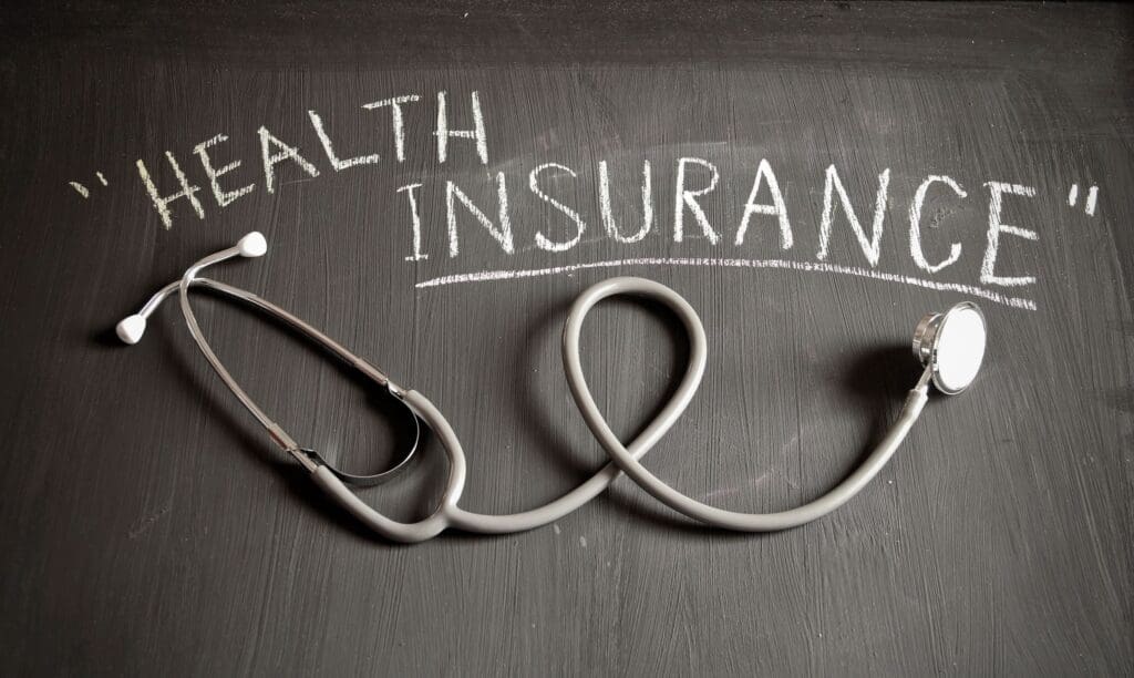 Stethoscope and chalkboard: Health insurance.