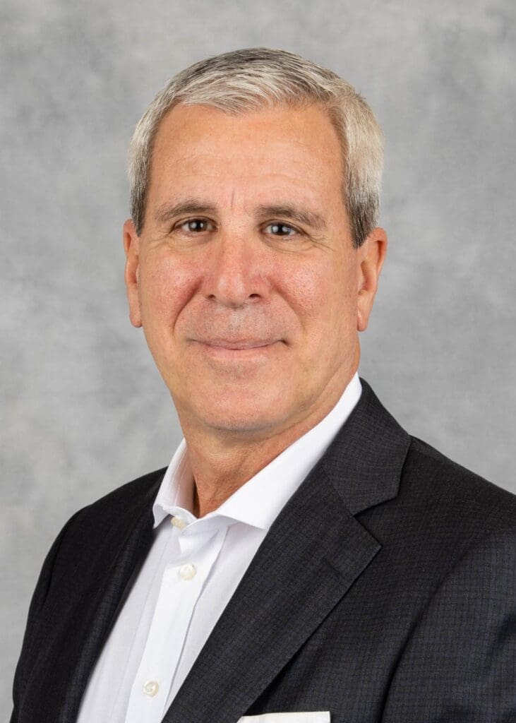 A man with white hair and wearing a suit.