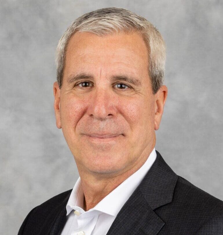 A man with white hair and wearing a suit.