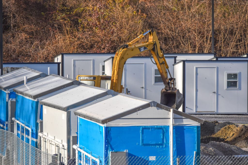 A blue and white building with a yellow excavator in the back.