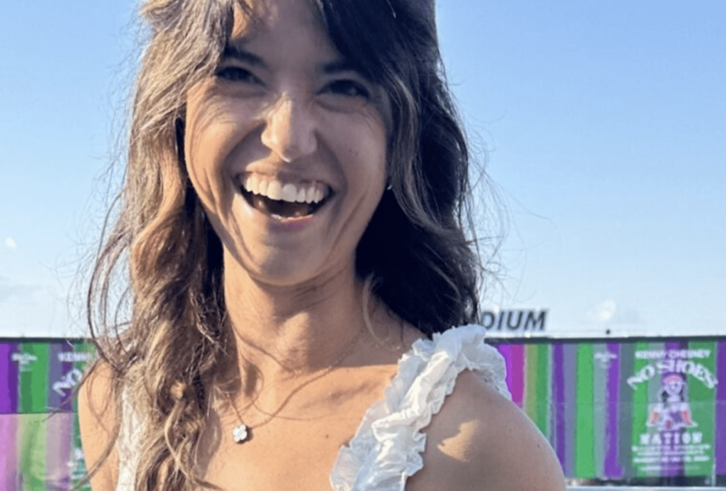 A woman smiling for the camera with her hair in front of a building.