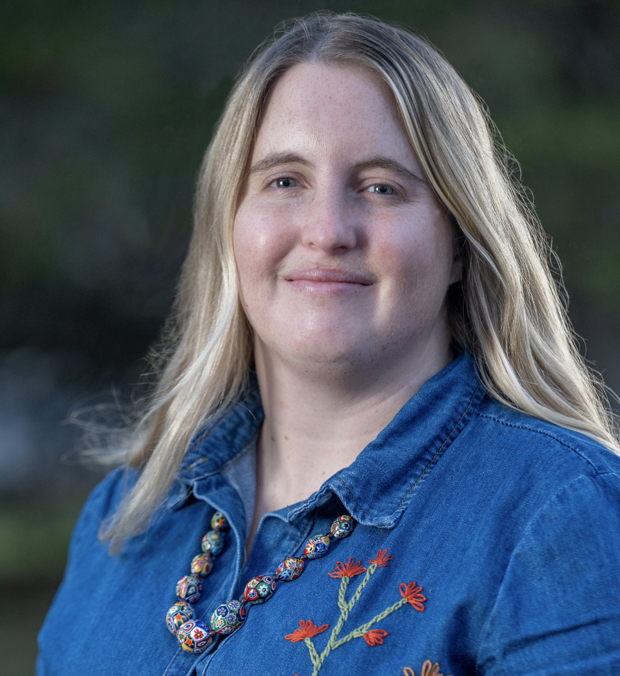 A woman with long blonde hair wearing a blue shirt.