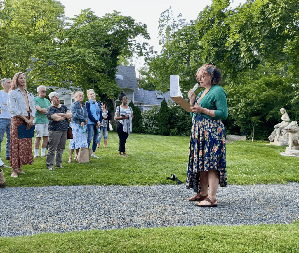 A woman standing on the side of a road holding papers.