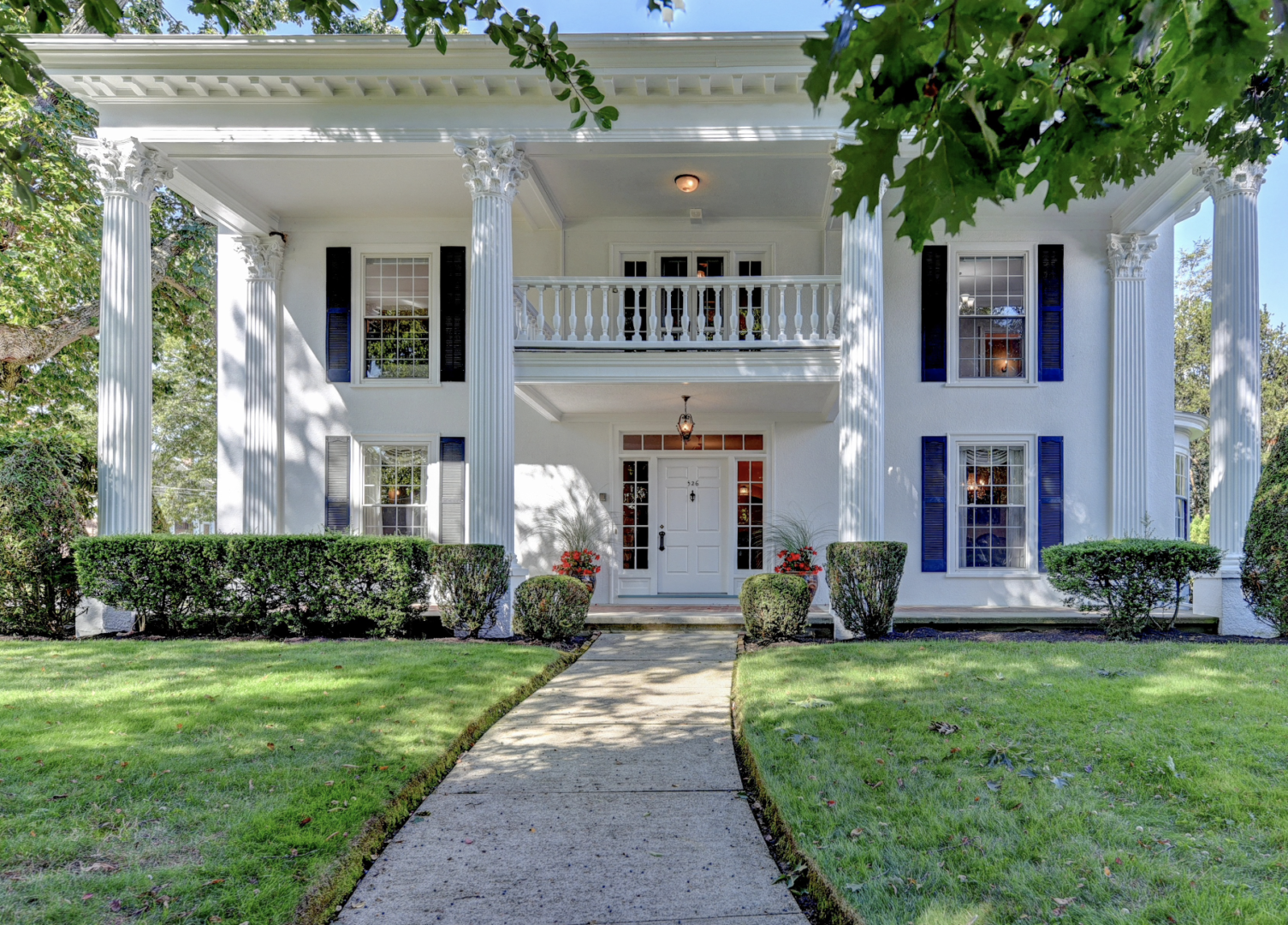 Screen Shot 2024-12-19 at 4.08.42 PM A white house with blue shutters and a porch.
