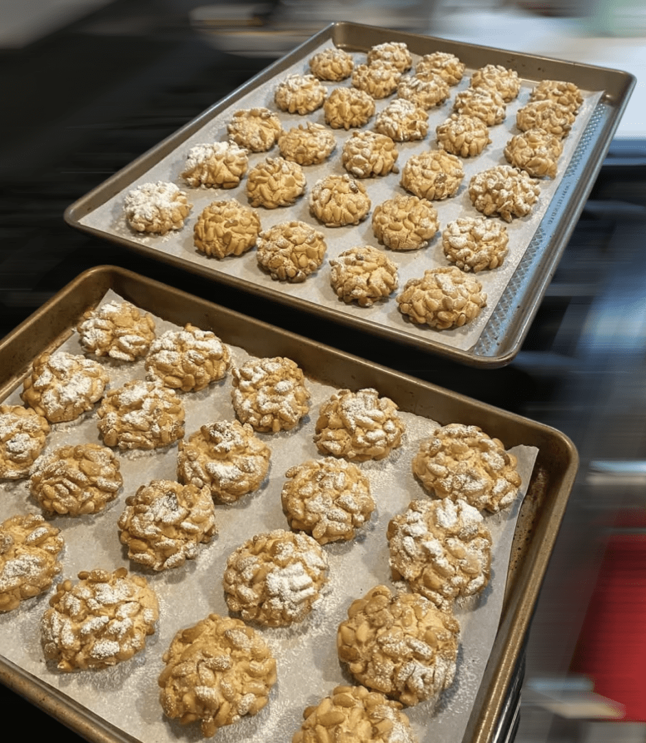 Two trays of cookies are on a counter.