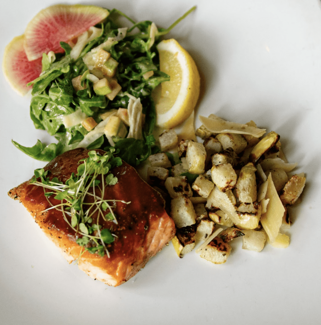 A plate of food with salmon, potatoes and salad.