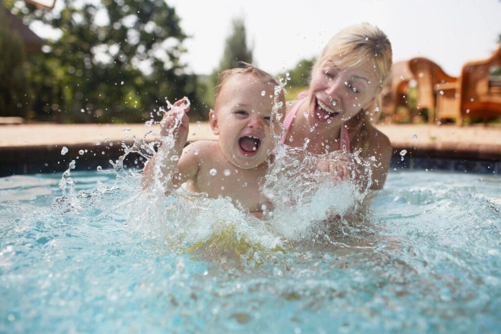 Two children playing in a pool with water splashing around them.