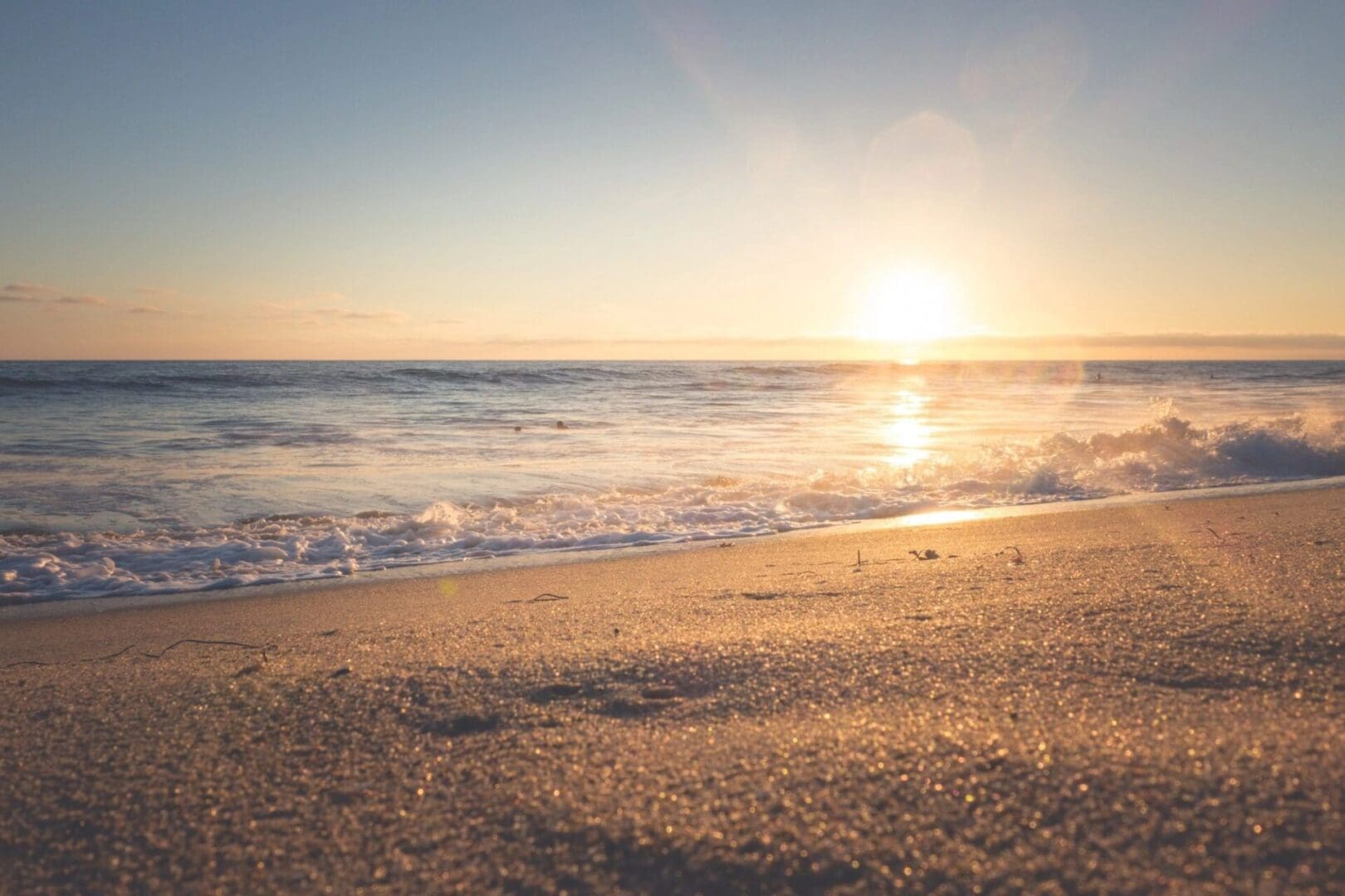 A beach with the sun setting in the background.