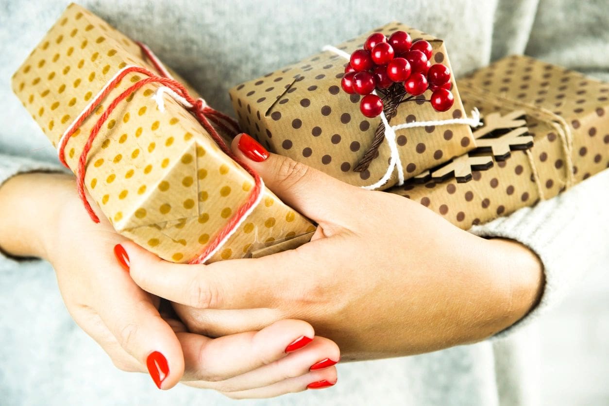 A woman holding some wrapped gifts with red berries on them.