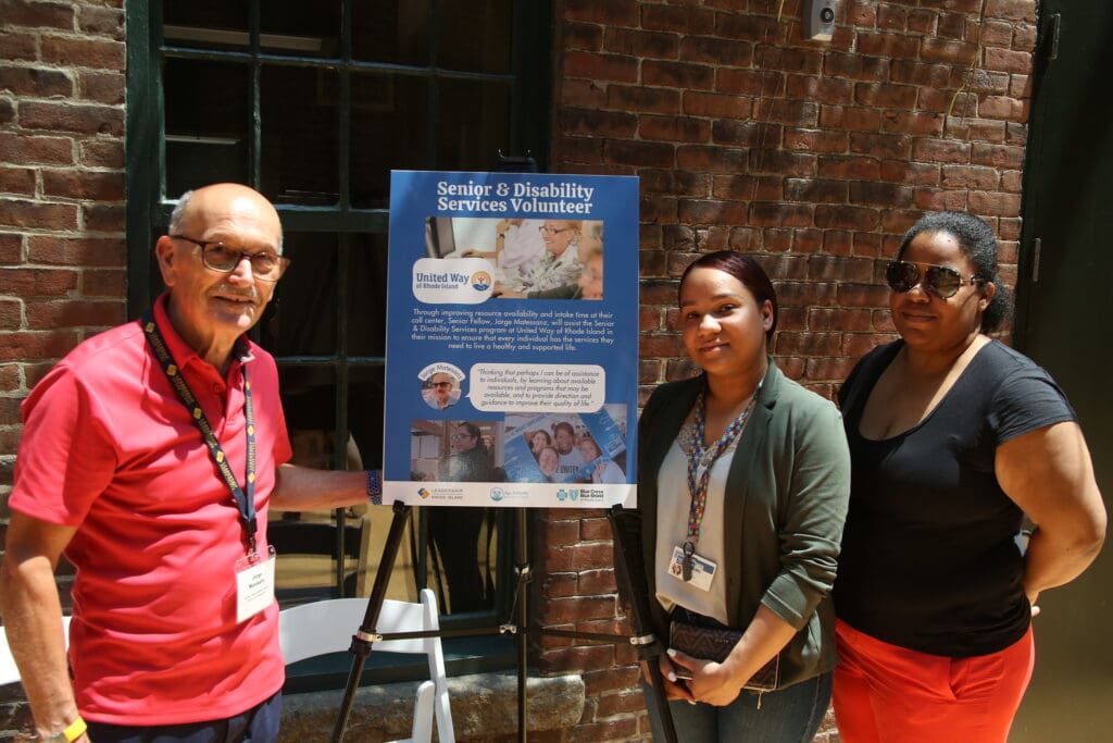 Three people standing next to a sign.