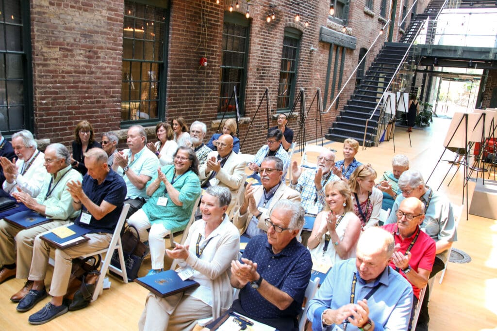 A group of people sitting in chairs and clapping.