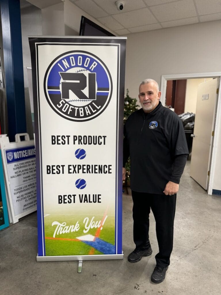 A man standing next to a sign that says indoor softball.