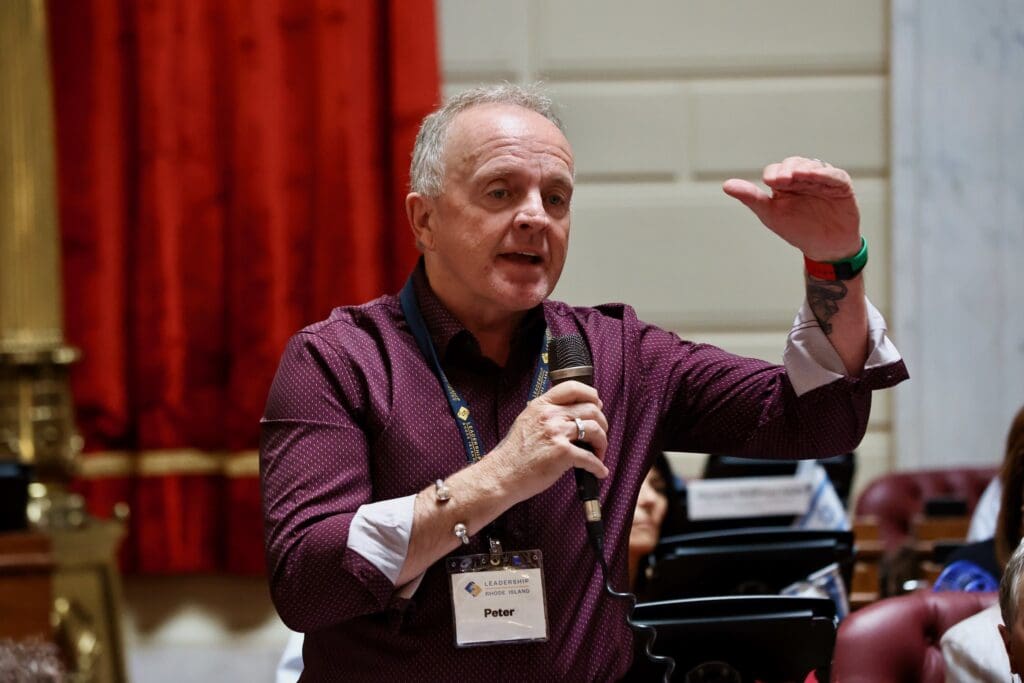 A man in purple shirt holding a microphone.