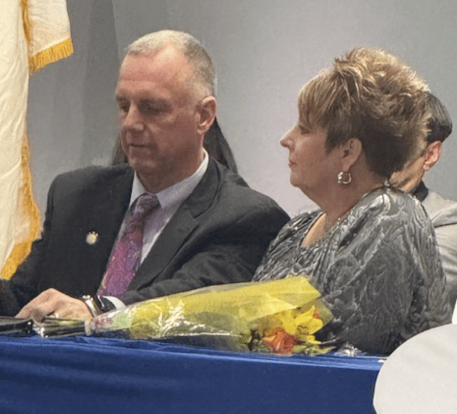 A man and woman sitting at a table with flowers.