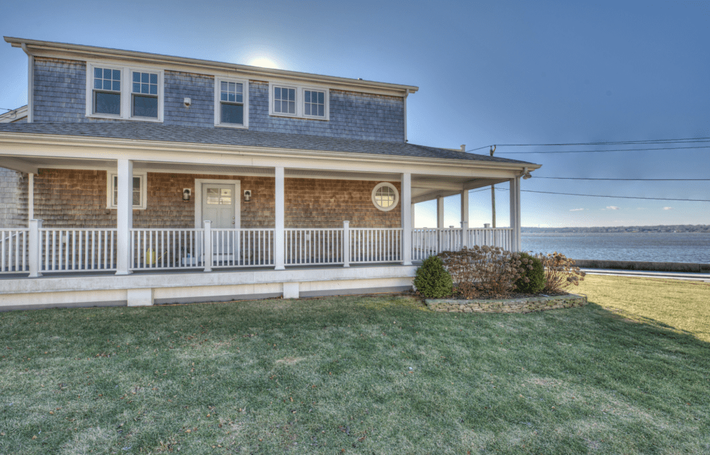 A house with grass and a clock on the front porch.