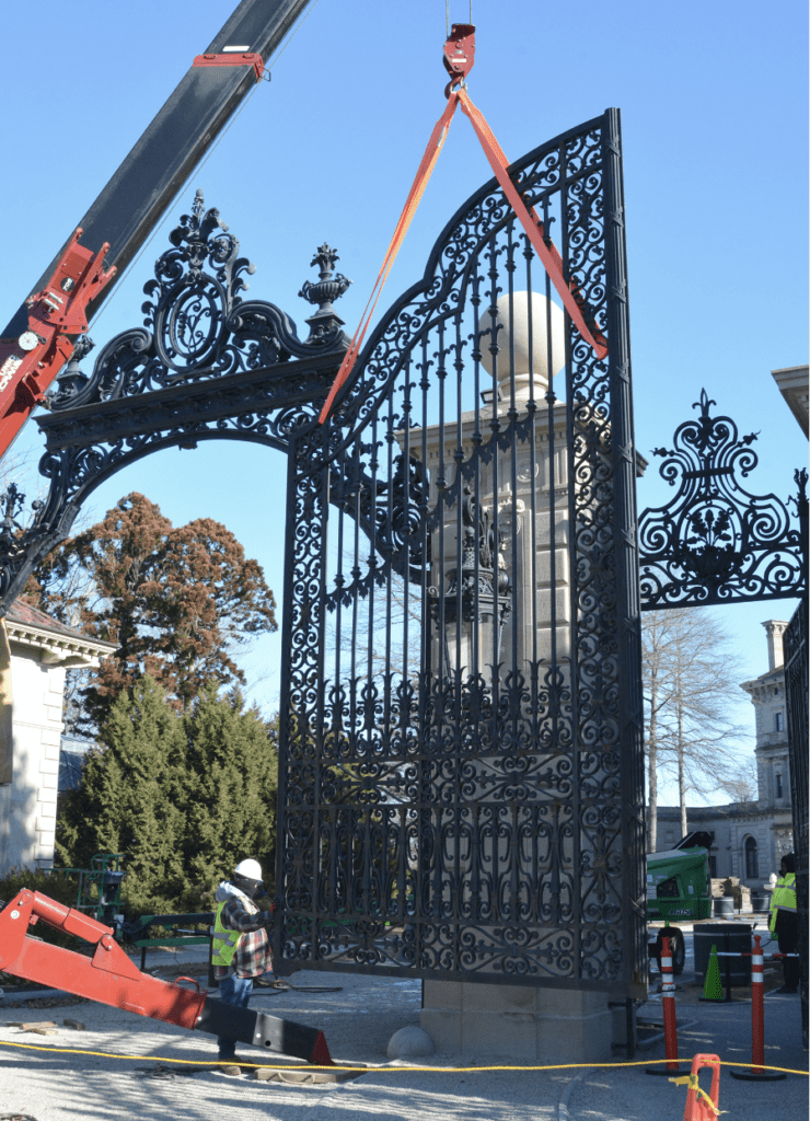 A crane is lifting the iron gate into place.