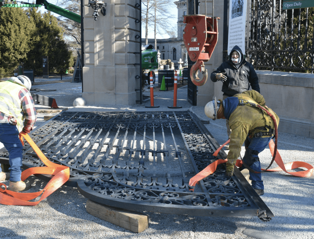 A man working on the bottom of an iron gate.