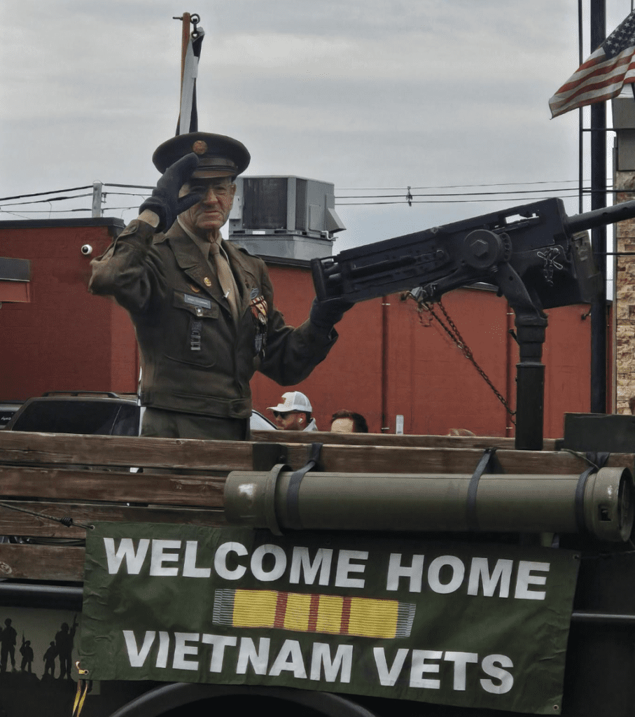 A man in uniform saluting while holding an m 1 9 grenade.